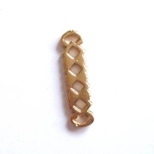 May include: A gold-colored metal jewelry finding with a diamond-shaped pattern. The finding has a rectangular shape with rounded ends and small loops at each end. The design features open diamond shapes.