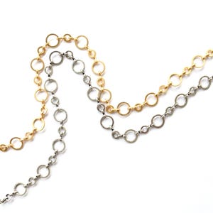 May include: Two delicate necklaces with open circle links. One necklace is gold-toned, and the other is silver-toned. The chains are displayed against a white background, highlighting the jewelry's design and color contrast. Ideal for layering or wearing separately.