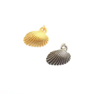 May include: Two seashell charms. One is gold-colored, the other is silver-colored. Both charms have a loop at the top for attaching to a necklace or bracelet. The shells have a detailed, ridged texture.