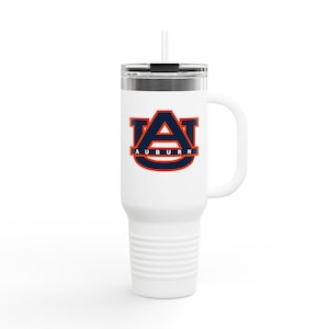 Puede incluir: Vaso térmico blanco con asa y pajita. El vaso presenta el logotipo de la Universidad de Auburn en azul marino y naranja. El logotipo está centrado en el vaso. El vaso tiene una tapa plateada y un asa blanca.