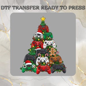 May include: A DTF transfer design showing a Christmas tree constructed from various video game controllers. The controllers are in red, green, black, and white, adorned with festive decorations such as a Santa hat and a gingerbread man. A gold star sits at the top.