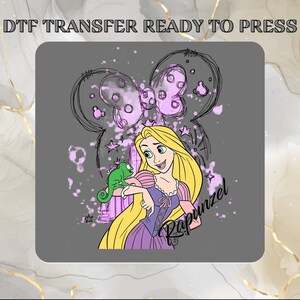May include: A DTF TRANSFER READY TO PRESS graphic featuring a cartoon character with long blonde hair and a purple dress, accompanied by a small green lizard. The design includes a sketch-style bow outline, purple paint splatters, and the name Rapunzel.
