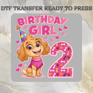 May include: DTF transfer ready to press. A cartoon puppy wearing a party hat and pink shirt, with the words "BIRTHDAY GIRL" and the number "2". Pink hearts and bone graphics complete the design.