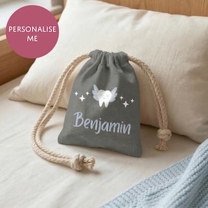 May include: A gray drawstring bag with a tooth fairy design, featuring a tooth with wings and the name "Benjamin" in white script. The bag has a beige drawstring closure and is set against a neutral background.