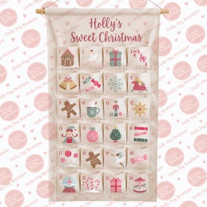 May include: A cream-coloured fabric advent calendar hanging from a wooden rod, featuring the text Holly's Sweet Christmas and twenty-four numbered pockets. Each pocket displays a unique holiday-themed illustration, including gingerbread, gifts, and candy.