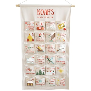 May include: A cream-colored fabric Santa Tracker advent calendar with the name "Noah's" in red. It features 24 numbered pockets with festive illustrations and text, including images of Santa and the North Pole.