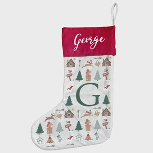 Puede incluir: Un calcetín navideño con puño rojo y cuerpo blanco. El cuerpo está estampado con ilustraciones del bosque, incluyendo casas, árboles y animales. El nombre "George" está impreso en blanco sobre una gran "G" verde.