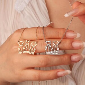 May include: Two personalized pet necklaces. One gold-toned necklace features three pet silhouettes with names: Fiona, Harley, and Memphis. The other silver-toned necklace has two pet silhouettes with names: Athena and Noodle.