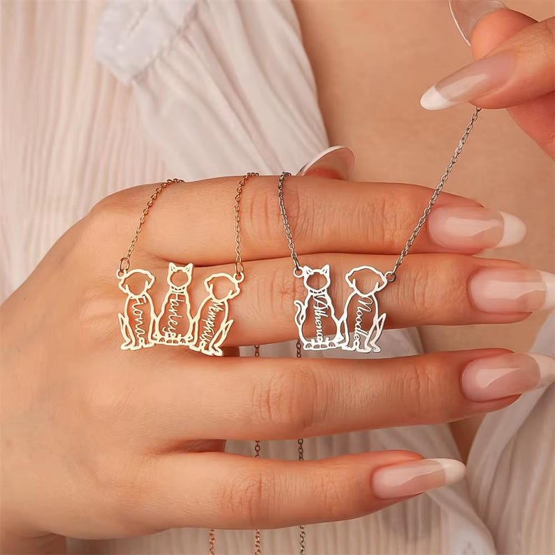 May include: Two personalized pet necklaces. One gold-toned necklace features three pet silhouettes with names: Fiona, Harley, and Memphis. The other silver-toned necklace has two pet silhouettes with names: Athena and Noodle.