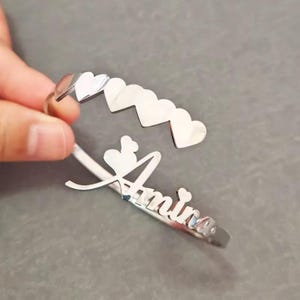 Könnte beinhalten: Ein Set aus drei Keramikbechern mit gesprenkelter, matter Oberfläche. Die Becher sind in den Farbtönen Creme, Hellgrau und Dunkelgrau gehalten. Jeder Becher hat ein schlichtes, minimalistisches Design und einen abgerundeten Henkel.