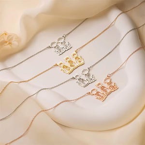 May include: Several delicate necklaces with cat-shaped pendants. Each pendant is a silhouette of cats with personalized names. The necklaces are in silver, gold, and rose gold tones, displayed on a white surface with a soft, neutral background.