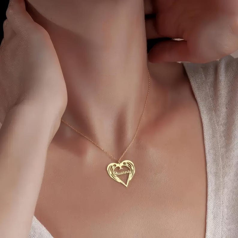 Puede incluir: Un collar con colgante en forma de coraz&oacute;n de color dorado con el nombre "Brianna" inscrito en su interior. El collar presenta una delicada cadena y se lleva alrededor del cuello. El colgante tiene un dise&ntilde;o de alas.