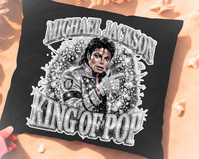 Op de afbeelding: Zwart kussen met een afbeelding van Michael Jackson met de tekst "MICHAEL JACKSON" boven zijn afbeelding en "KING OF POP" eronder. De afbeelding is in zwart-wit met sprankelende accenten.