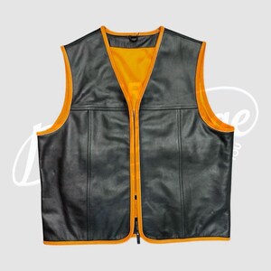 May include: Black leather vest with a bright orange interior and trim. The vest has a V-neck, a full-length zipper, and two horizontal seams across the front. The vest is sleeveless and has a classic biker style.
