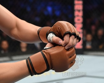 May include: Brown leather MMA gloves with black trim. The gloves are worn by a person in a fighting ring. The gloves have a wrist strap and finger openings. The image includes the text "LEATHERHIGH".