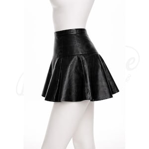 Puede incluir: Minifalda de cuero negro con dise&ntilde;o acampanado y plisado. La falda se muestra sobre un maniqu&iacute; sobre un fondo blanco. La falda tiene una cintura alta y un dobladillo corto y coqueto.