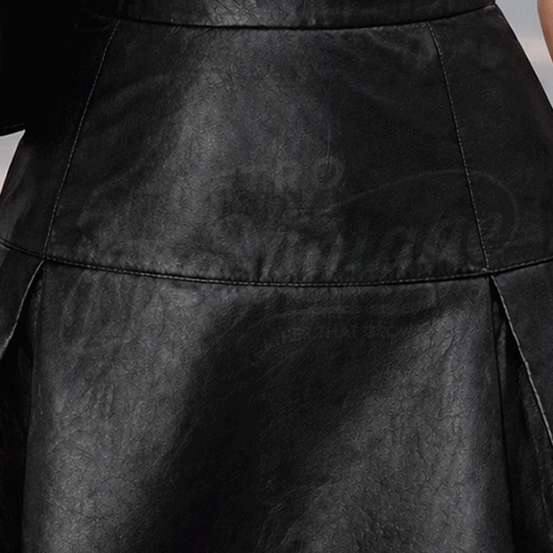 Puede incluir: Primer plano de una falda de cuero negro. La falda tiene una superficie texturizada y un ligero brillo. Los pliegues son visibles y el dise&ntilde;o general es elegante y moderno. El texto "LEATHER MATTERS" es visible.