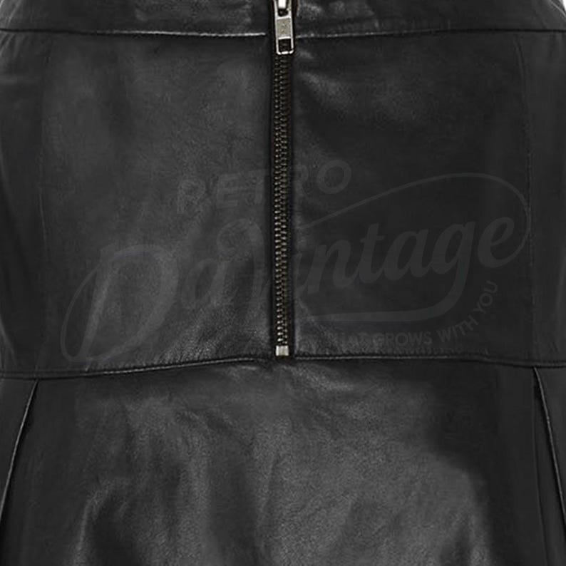 Puede incluir: Primer plano de una falda de cuero negro con cremallera vertical. La falda tiene un dise&ntilde;o plisado y un brillo sutil. El texto "Retro Vintage" es visible en el fondo.