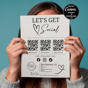 May include: A white flyer with the text "LET'S GET Social" and social media QR codes for Facebook, Instagram, and TikTok. The flyer includes the text "LIKE | FOLLOW I TAG" and a space for a business logo. The flyer is held in front of a person.