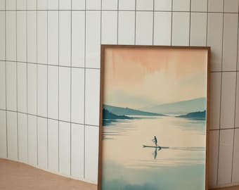 May include: A framed art print depicts a serene lake scene with a person paddleboarding. The artwork features a muted color palette of blues, greens, and peach, with a wooden frame. The image evokes a sense of tranquility and outdoor recreation.