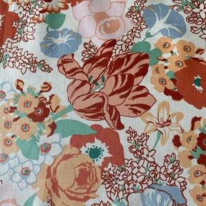 May include: A close-up of a floral pattern featuring a variety of flowers in shades of orange, red, pink, blue, and green against a white background. The design includes tulips, roses, and other floral elements.