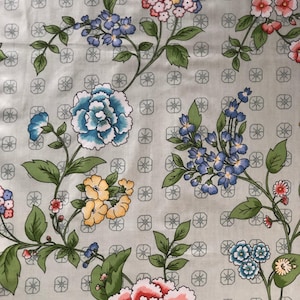 Könnte beinhalten: Stoff mit floralem Muster in Blau, Rosa, Gelb und Grün. Der Hintergrund ist hellgrau mit einem sich wiederholenden geometrischen Muster. Geeignet für Nähprojekte und Bastelarbeiten.