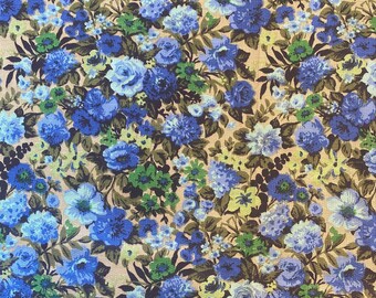 May include: A fabric with a dense floral pattern. The design features various shades of blue flowers, including roses and other blooms, set against a tan background. Green foliage accents the blue flowers, creating a vibrant and detailed textile.