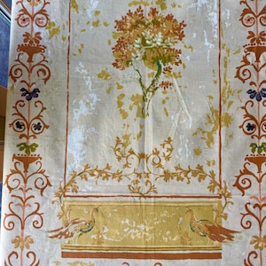 Könnte beinhalten: Ein Stoff im Vintage-Stil mit cremefarbenem Hintergrund und einem zentralen Design mit einem Baum mit orangefarbenem und gelbem Laub. Der Stoff hat dekorative Bordüren mit floralen und Scrollmustern in Braun-, Orange- und Lilatönen. Unten sind zwei Vögel abgebildet.