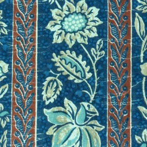 Könnte beinhalten: Nahaufnahme eines Stoffes mit floralem Muster. Das Design zeigt große Blumen und Blätter in Blau-, Türkis- und Beigetönen vor einem dunkelblauen Hintergrund. Vertikale Streifen mit einem rotbraunen Rand und einem weißen Blumenmuster sind ebenfalls vorhanden.