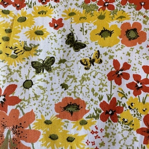 Könnte beinhalten: Weißer Stoff mit floralem Muster. Das Muster zeigt gelbe und orangefarbene Blumen, grüne Blätter und Schmetterlinge. Die Blumen variieren in Größe und Form, mit detaillierten Blütenblättern. Schmetterlinge sind in Grün- und Gelbtönen gehalten.