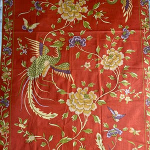 Könnte beinhalten: Roter Stoff mit Blumen- und Vogelmuster. Der Stoff zeigt große gelbe Blumen, violette Akzente, grüne Blätter und stilisierte Vögel. Das Design ist symmetrisch, mit einem Rand aus Blumen und Blättern.