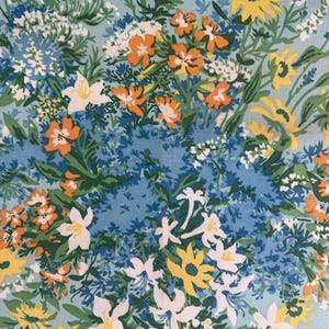 Könnte beinhalten: Ein Blumenmuster mit gelben, orangefarbenen, weißen und blauen Blumen auf hellblauem Hintergrund. Das Muster zeigt eine Vielzahl von Blüten und Blättern und schafft ein lebendiges und farbenfrohes Design. Ideal für Stoff oder Tapeten.