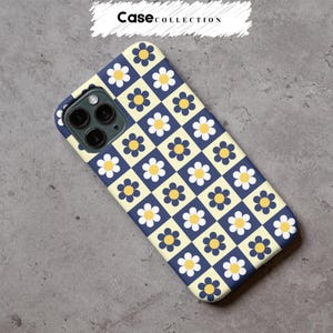 May include: A phone case with a daisy pattern. The case has a grid of navy blue and light yellow squares, each with a daisy with a yellow centre and white petals. The text "Case Collection" is at the top.