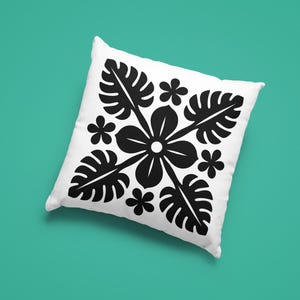 May include: White square pillow with a black floral and leaf pattern. The design features a central flower with radiating leaves and smaller flowers, set against a teal background.
