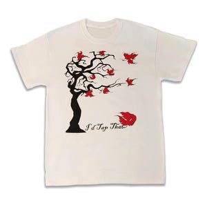 Könnte beinhalten: Cremefarbenes T-Shirt mit einem schwarzen Baumdesign und roten Blättern, versehen mit dem Schriftzug "I'd Tap That". Die Grafik zeigt stilisierte Vögel und einen Windeffekt. Ein lässiges T-Shirt für den Alltag.