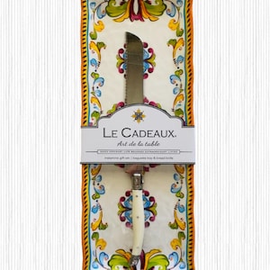 May include: A decorative baguette tray and bread knife set. The tray has a colorful floral design with orange, yellow, blue, and green accents. The knife has a serrated blade and a white handle. The packaging reads "LE CADEAUX. Art de la table."