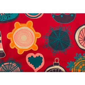 May include: A red fabric with a repeating pattern of Christmas ornaments in various shapes and colors. The ornaments include bells, baubles, and starburst designs in teal, orange, pink, and navy blue.