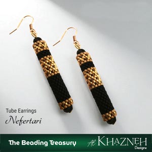 May include: A pair of tube earrings with a black and gold beaded design. The earrings have a cylindrical shape with gold-coloured metal hooks. The text "Tube Earrings Nefertari" is visible.