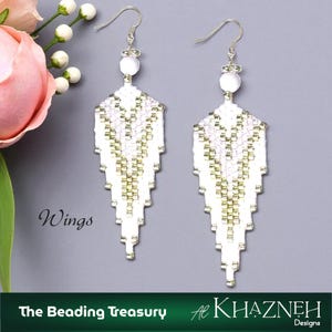 May include: A pair of white beaded dangle earrings with a wing-like design. The earrings have silver-colored hooks and a white bead at the top. The design incorporates gold and white beads. The word "Wings" is written on the image.