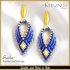 Può includere: Un paio di orecchini Sasha Russian Leaf. Questi orecchini pendenti presentano un design a forma di foglia realizzato con perline blu e oro. Gli orecchini hanno una parte superiore gialla e un motivo a forma di diamante al centro. Il testo "Sparkle and Shine in Style" è in basso.