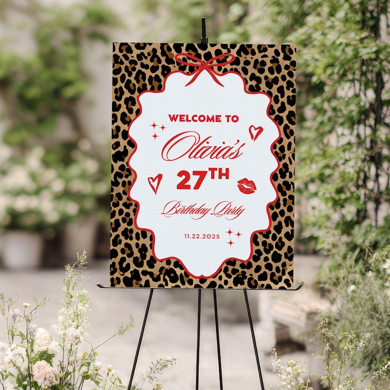 Puede incluir: Un letrero de bienvenida para una fiesta con un fondo de estampado de leopardo y un centro blanco festoneado. El letrero dice "Bienvenida a la fiesta de cumplea&ntilde;os n&uacute;mero 27 de Olivia" en escritura roja, con corazones, estrellas y un lazo decorativos.