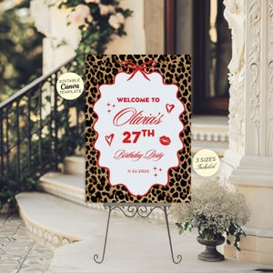 Puede incluir: Un letrero de bienvenida para una fiesta con un fondo de estampado de leopardo y un centro blanco festoneado. El letrero dice "Welcome to Olivia's 27th Birthday Party" en letras rojas. Decorado con un lazo y corazones rojos.