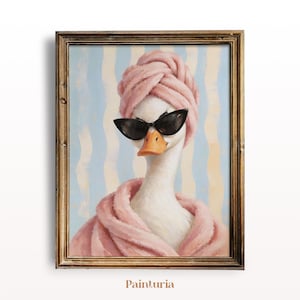 May include: A framed wall art print featuring a white goose wearing a pink towel wrapped around its head and a matching pink bathrobe. The goose is wearing black cat-eye sunglasses. The background consists of vertical light blue and cream stripes.