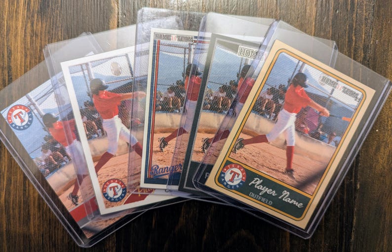 May include: Baseball trading cards featuring a player in a red uniform swinging a bat. The cards are in protective sleeves, with the Texas Rangers logo visible. The cards are on a wooden surface.