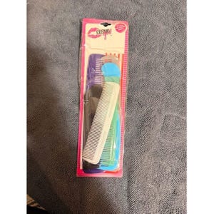 May include: A package of assorted hair combs in various colors, including white, black, blue, and purple. The combs are packaged in a pink and clear plastic sleeve with the Cosmo logo.