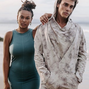 Peut inclure: Un homme et une femme debout sur une plage. L'homme porte un sweat &agrave; capuche gris clair avec un motif tie-dye. La femme porte une robe sans manches turquoise.