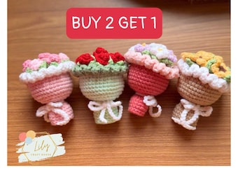 Può includere: Quattro bambole all'uncinetto a forma di vaso di fiori, rosa, verdi, rosse e marroni. Ogni bambola ha una diversa composizione floreale e un fiocco bianco. Il testo "BUY 2 GET 1" è in un rettangolo rosso. Il logo Lily Craft House è in basso a sinistra.