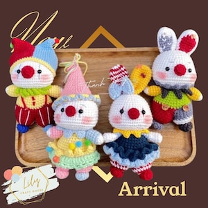 May include: Four handmade crochet clown and bunny dolls in a wooden tray. The dolls have white faces, red noses, and colorful outfits. The text "Arrival" is at the bottom of the image. The Lily Craft House logo is in the bottom left corner.