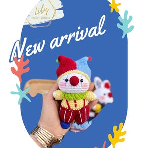 May include: A handmade crochet clown doll with a red, yellow, and blue color scheme. The doll has a white face with a red nose and is wearing a jester hat. The words "New arrival" are written in white cursive font.