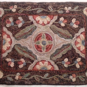 Puede incluir: Una alfombra rectangular, hecha a mano, con un fondo marr&oacute;n oscuro y un dise&ntilde;o floral central. La alfombra presenta un borde y un medall&oacute;n central con motivos florales y de hojas en tonos rojos, azules, verdes y beige. Las dimensiones de la alfombra no son visibles.